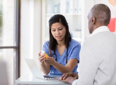 Care providers can log in easily online, pharmacist at computer talking to worker